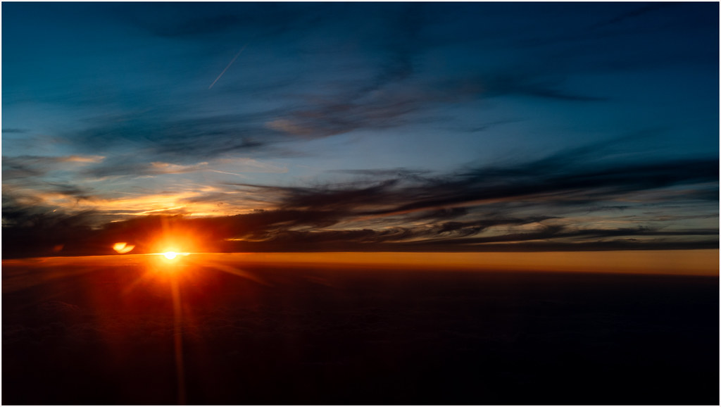 An airplane wing above the clouds at sunset